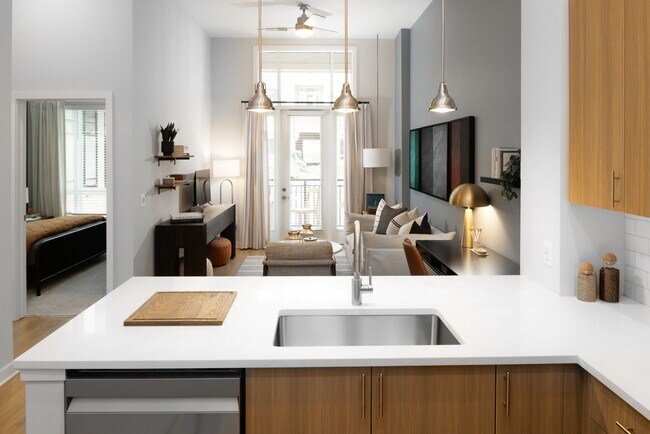 Kitchen and living area with oak cabinetry, white quartz countertops, and pendant lighting