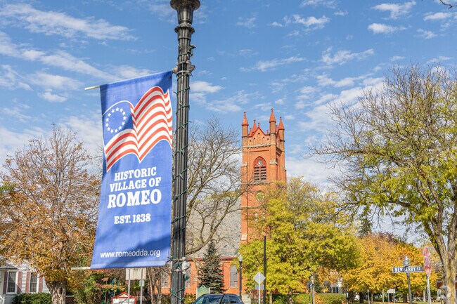 A patriotic sign shines brightly in Romeo with First Congregational Church in the background.