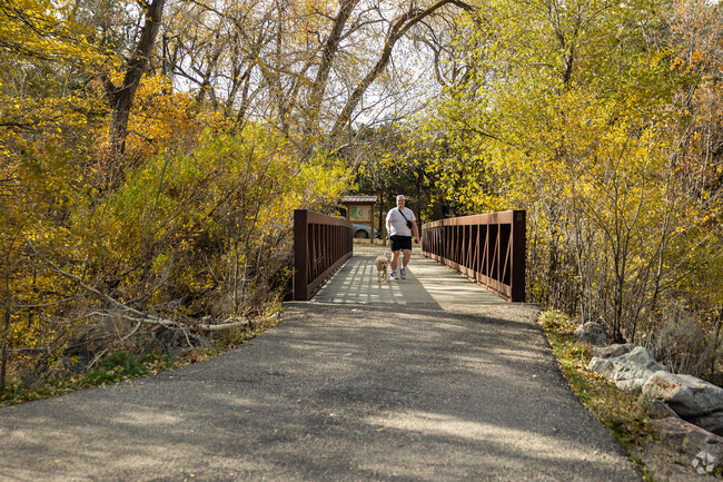A man walks his dog across a bridge at a park in East Bench.