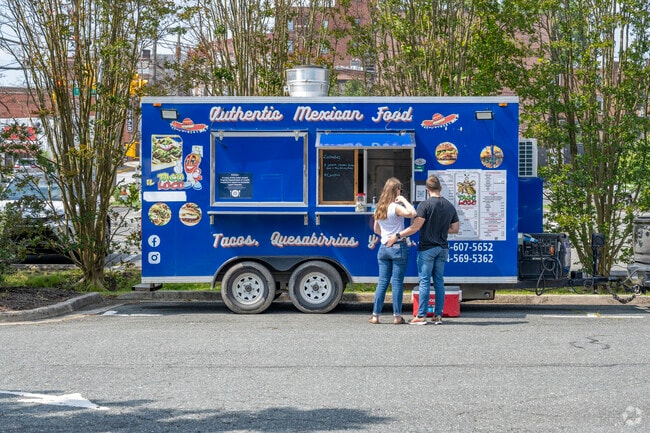 Food trucks set up shop in the farmer's market square selling tasty treats like tacos.