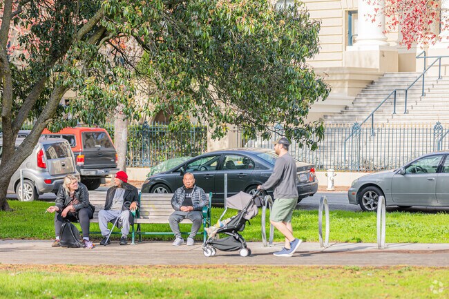 Peaceful stroll with a stroller, friends enjoying a bench in the Panhandle.