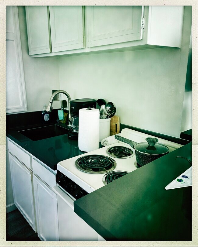 Small kitchenette with 4 burner stove and oven, pots, pans, utensils and coffee maker