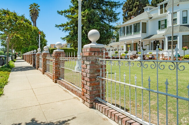 A brick and decorative iron fence is featured outside this Queen Anne style home in the Oval.