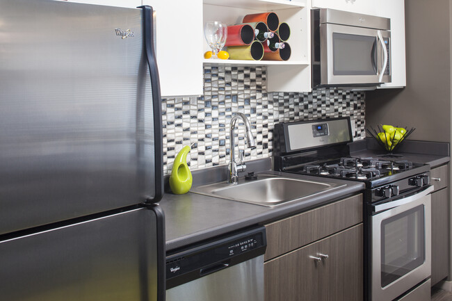 Classic Package II kitchen with stainless steel appliances, dark laminate countertops, white and brown cabinetry, tile backsplash, and hard surface flooring