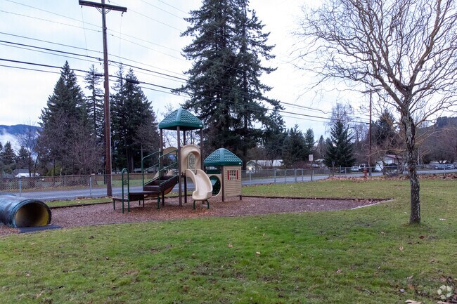 A play structure is enclosed in a grassy area for children to enjoy.