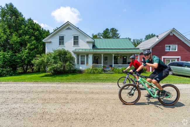 Cyclists ride past a classic farmhouse-style home in rural Huntington.