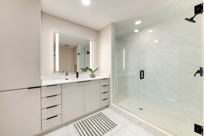 Tower Building - Renovated bath with white quartz countertop, light grey cabinetry, and tile flooring