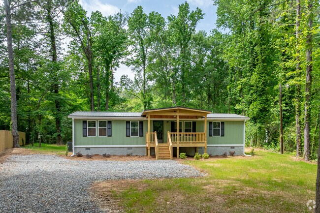 Nestled among tall pines, this charming manufactured home in Towaliga Shores features a welcoming front porch.