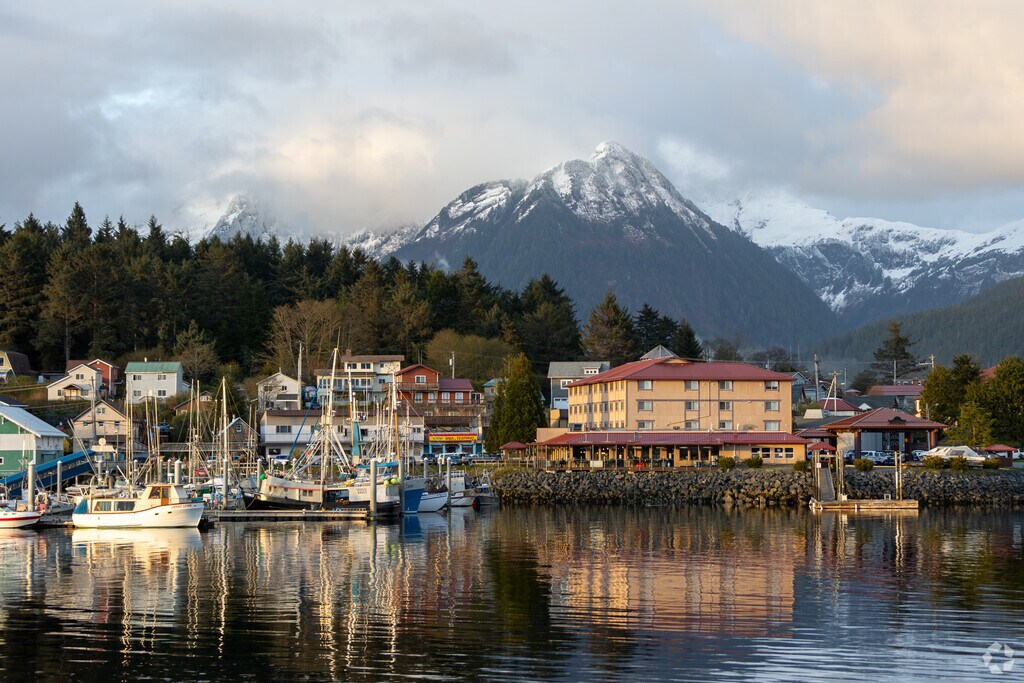 Fishing boats and waterfront homes frame the Sitka coastline under snow-capped mountains.