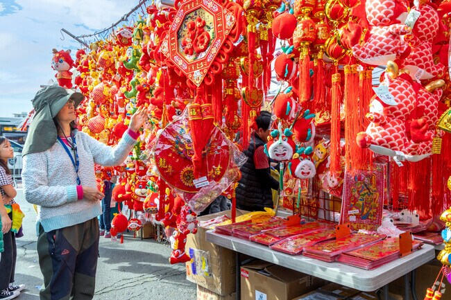 Visitors in Chinatown walk past booths selling tasseled Chinese lanterns and ornaments.