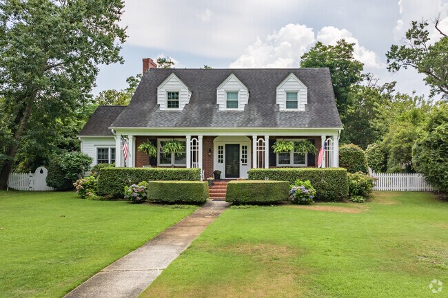 A Cape Cod-style home in Forest Hills South is showcased by a well-manicured lawn.