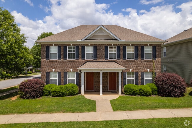 A large brick two-story colonial duplex sits on small plots in the area.