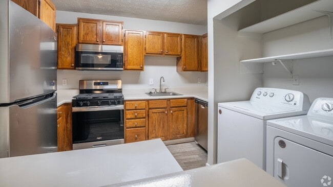 Kitchen featuring stainless steel appliances, warm wood cabinetry, and an in-unit washer and dryer for your convenience.