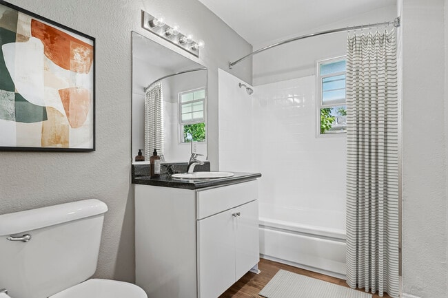 Bath with white cabinetry, black laminate countertops, and hard surface flooring