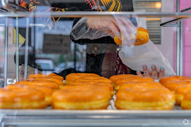 Worker packs a deliciously glazed breakfast for eager Woodside resident at Jasmine Donuts.