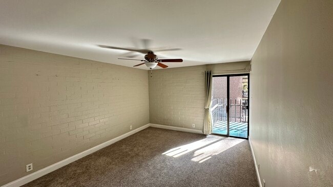 Large bedroom with ceiling fan and door to balcony