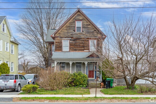 A single family colonial revival in Chicopee Center has a front porch and quaint green yard.