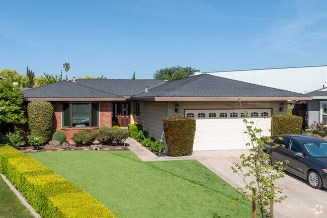 This Midcentury Ranch-style home in Cahalan features a brick facade and manicured landscaping.