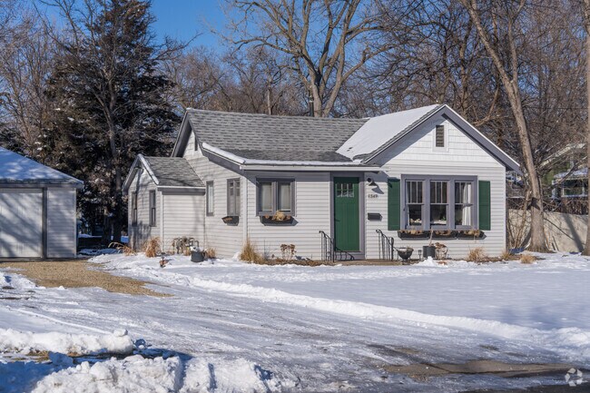 A small white house with a green door in the Cedarhurst neighborhood.