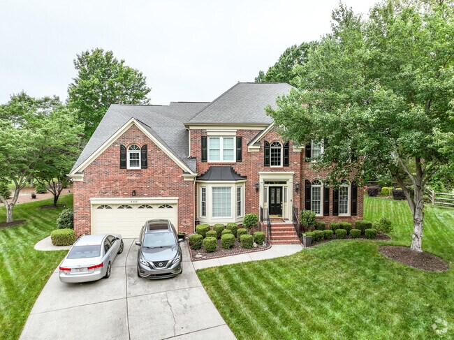 A large, stately brick home with mature trees and manicured home