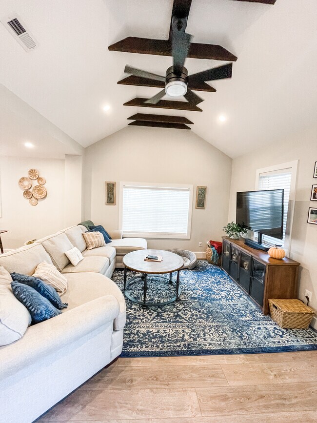 Vaulted ceiling in living room with original beams and ceiling fan