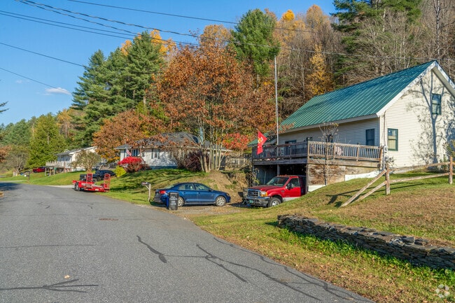 A row of homes in South Barre are surrounded by tall trees proving shade to residents' yards.