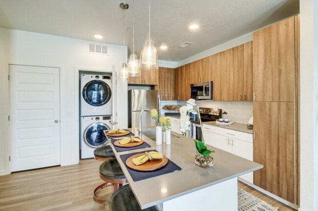 Kitchens feature oak upper and white lower cabinetry, grey quartz countertops, white subway tile backsplash, kitchen island or breakfast bar, and luxury vinyl plank flooring