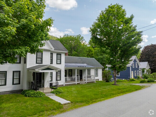 A row of homes in Dummerston reflects classic New England charm, with well-kept facades nestled among trees and rolling hills.