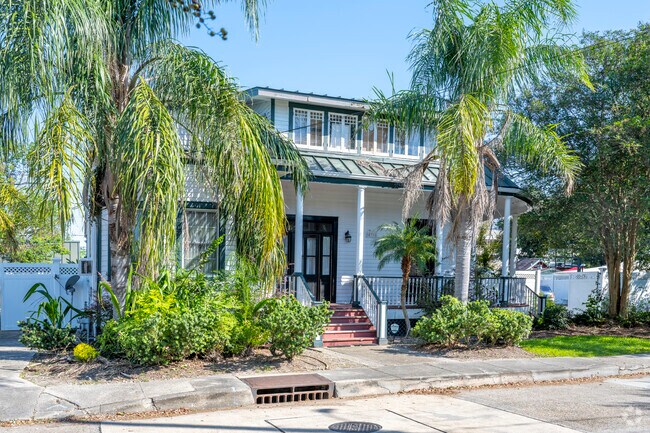 A cottage with an elegant front porch and some tropical plants out front.