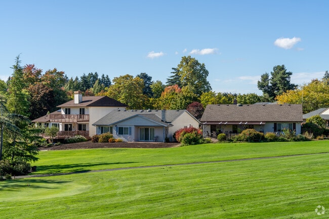Homes by the golf course sport tidy front lawns and shrubbery.