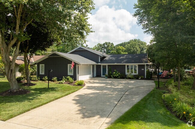 A ranch-style home is located in Reminderville, surrounded by mature shade trees.