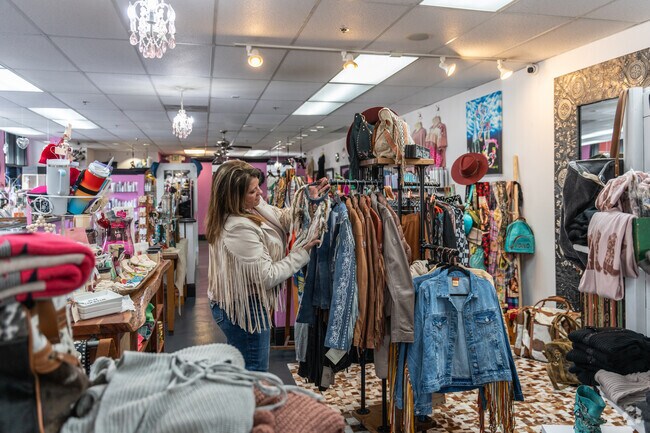 The owner of Uptown Girl Boutique and Salon arranges coats on the rack in Downtown Livermore.