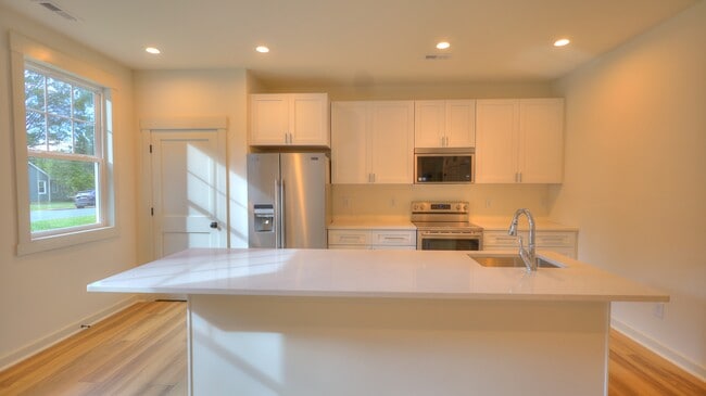 Unit A - Chef's kitchen with eat in island, quartz countertops and stainless appliances.