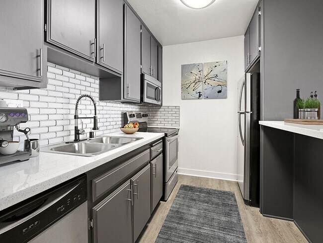 White tiled kitchen with stainless steel fridge, microwave, and oven.