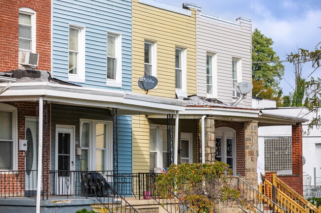 Colorful vinyl‑sided rowhomes line Gwynns Falls side streets.