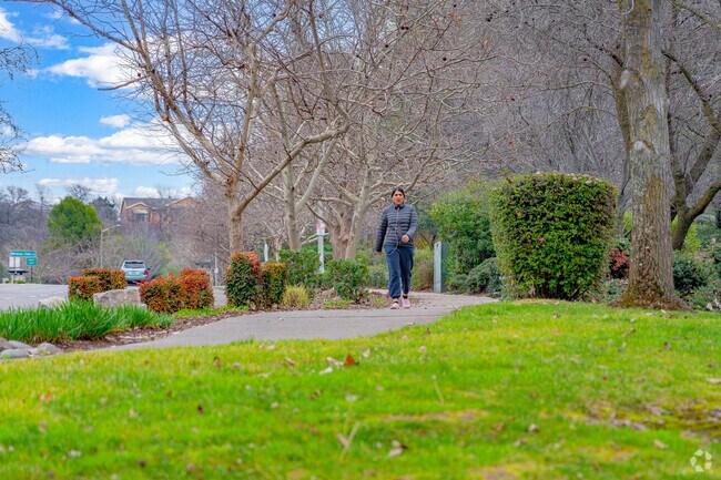 Woman enjoys stroll along peaceful walkway through Whitney Oaks.