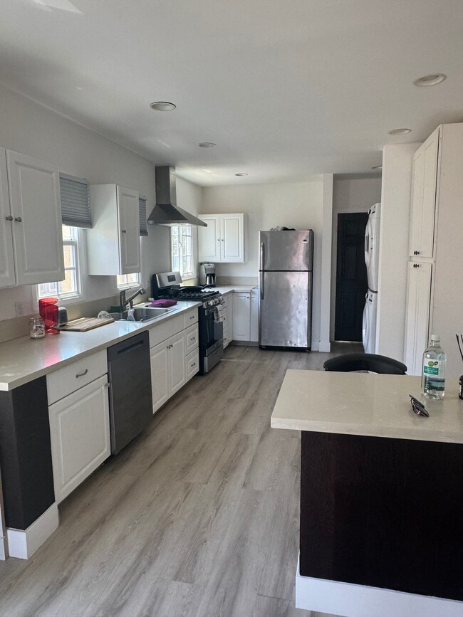 kitchen with stainless steel fridge, dishwasher, stove, oven & stacked washer & dryer; 4 seat island