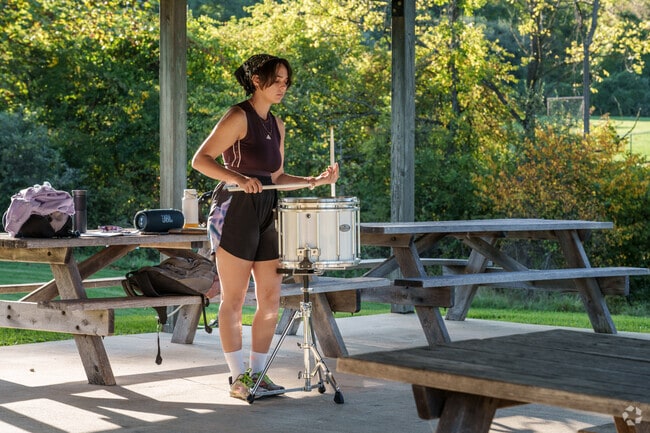A high school drummer practices her drills under a shaded pavilion in Frazer.