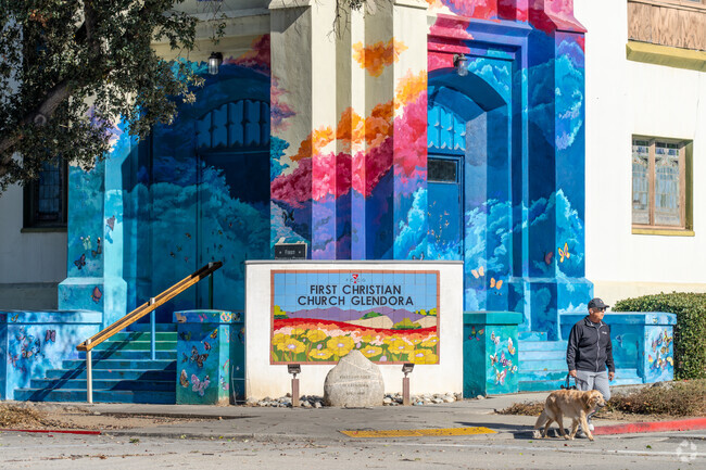 A vibrant church stands tall as a local strolls by with his dog through Glendora's streets.