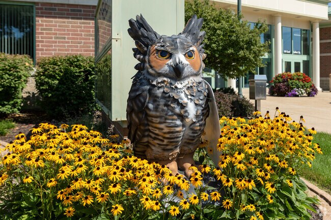 An owl statue surrounded by yellow flowers is featured at the Schererville Town Hall.