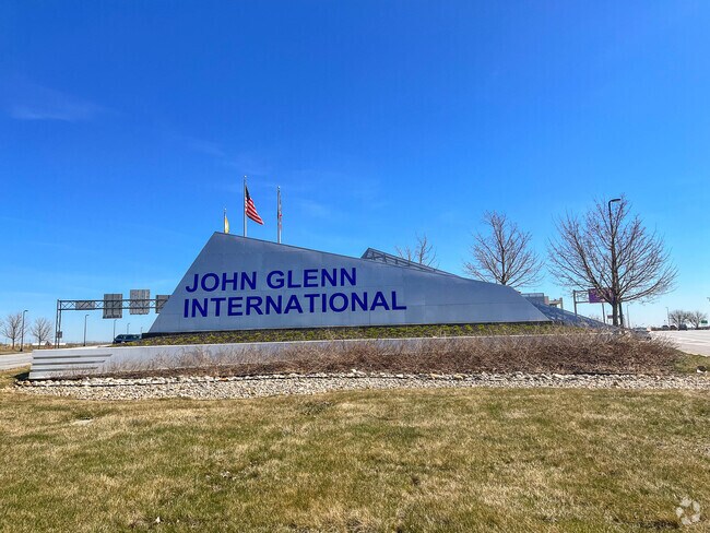 The John Glenn International Airport sign is visible from I‑670, guiding travelers to the terminal.