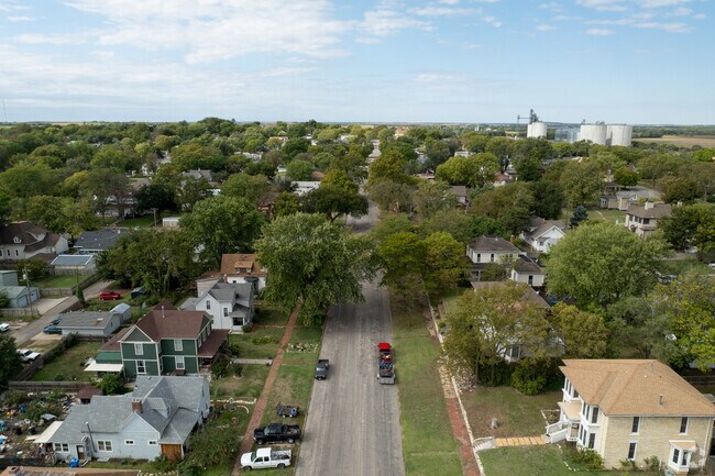 Residential streets are filled with various housing styles and tall trees.