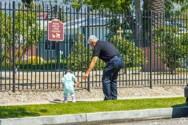 A family strolls hand in hand down the tree-lined streets of Rancho Riverside, soaking up the warm sunshine and the pleasant ambiance of the neighborhood.