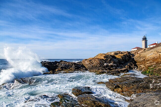 The waves break on the rocky shore of the Beavertail State Park in view of the Beavertail Lighthouse close to the East Shore Road neighborhood.