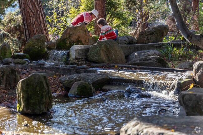 A mother and son play by a waterfall in the Torii Gate Garden in Adams Point Neighborhood.