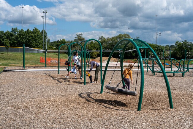 A young family enjoys the swings at Weiss Park near the Oak Place neighborhood.