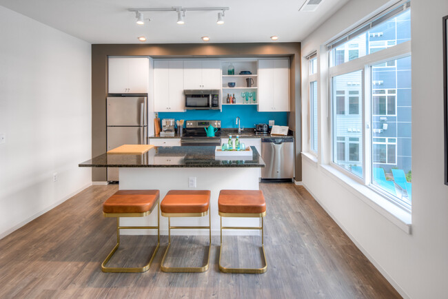 Kitchen with white cabinetry, granite countertops, island, stainless steel appliances and hard surface flooring