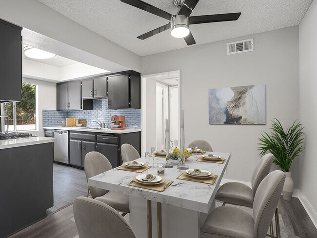 Hardwood floored dining room with ceiling fan and view of kitchen.