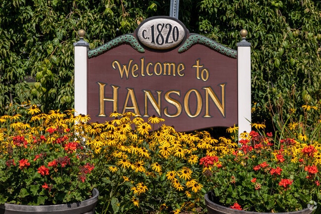 A colorful sign surrounded by flowers welcomes visitors to Hanson.