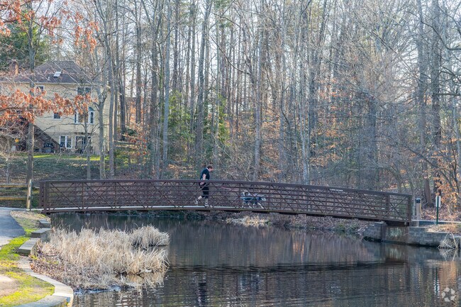 Locals enjoy the simple pleasures of a walk across the Westridge Pond bridge, surrounded by serene natural beauty.